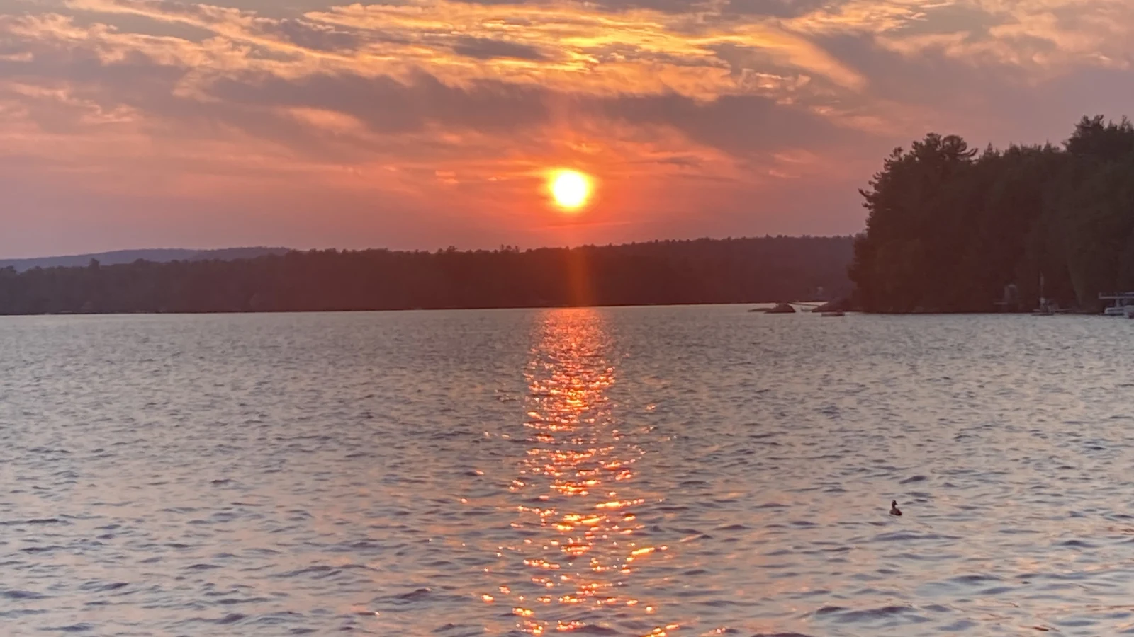 Sun setting over calm coastal Maine waters seen from a boat with an American flag