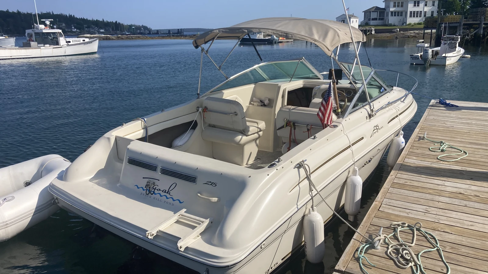 White 21-foot SeaRay powerboat named Goak docked at a Maine marina with an American flag