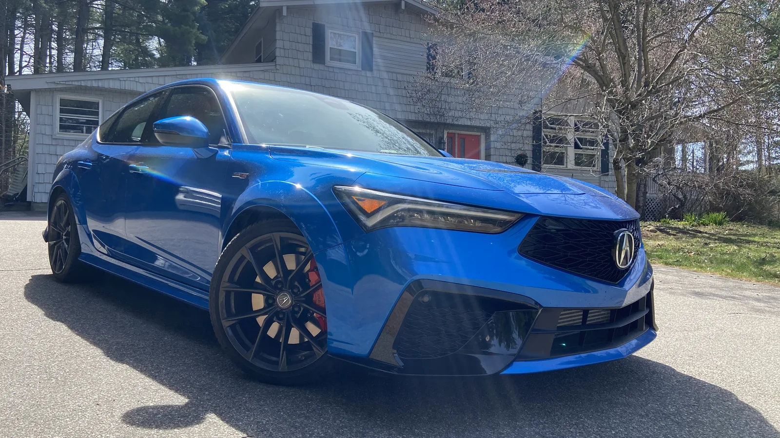 Double Apex Blue 2026 Acura Integra Type S sport sedan, front three-quarter view in a driveway.