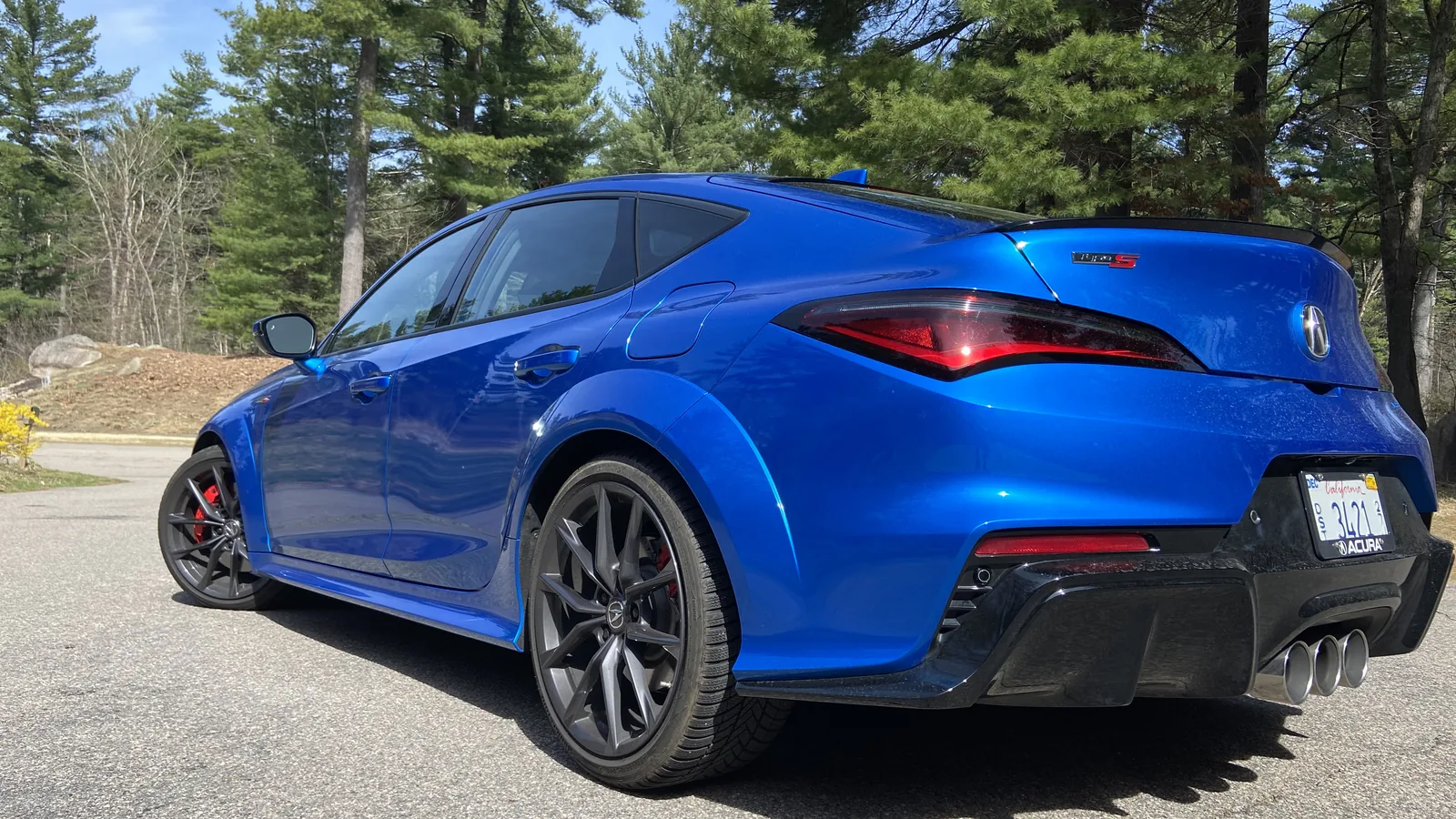 Rear three-quarter view of a blue 2026 Acura Integra Type S showing its liftback profile and rear diffuser.