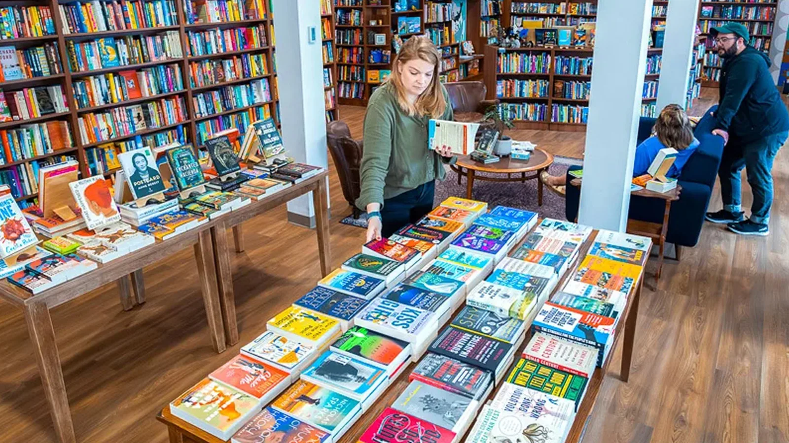 Customers browsing tables of colorful books inside Back Cove Books in Portland, Maine.