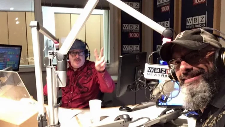 Automotive editor Craig Fitzgerald in the foreground with host Bradley Jay, in a red shirt, in the WBZ NewsRadio 1030 studio in Boston.
