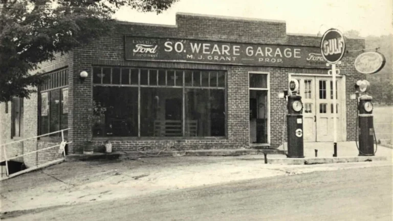 Vintage black and white photo of the brick South Weare Garage in Weare, New Hampshire, with a Ford dealership sign reading M.J. Grant Prop. and two Gulf gasoline pumps out front