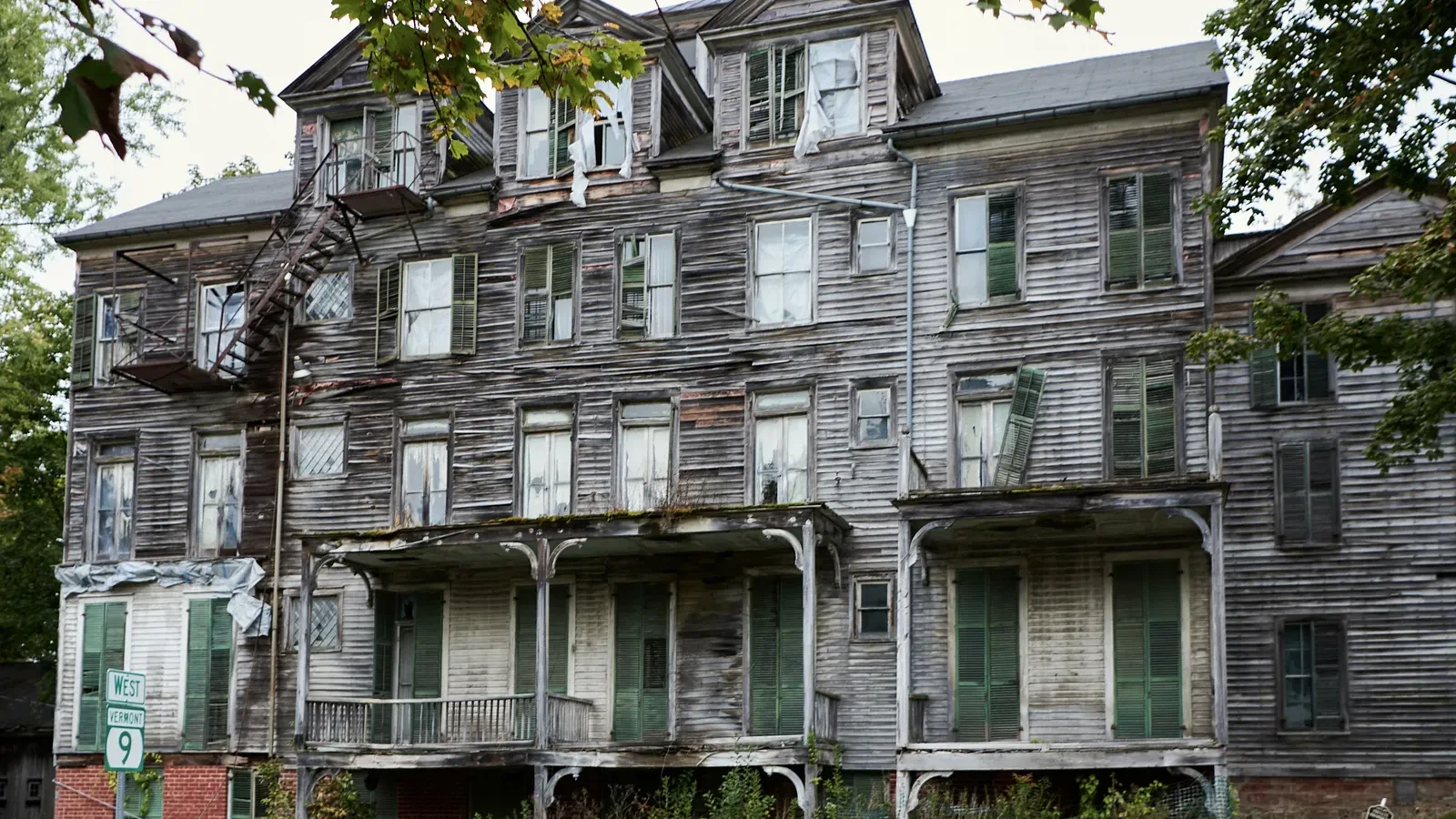 Weathered facade of the historic Walloomsac Inn with sagging porches, peeling paint, and green shuttered windows in Old Bennington, Vermont