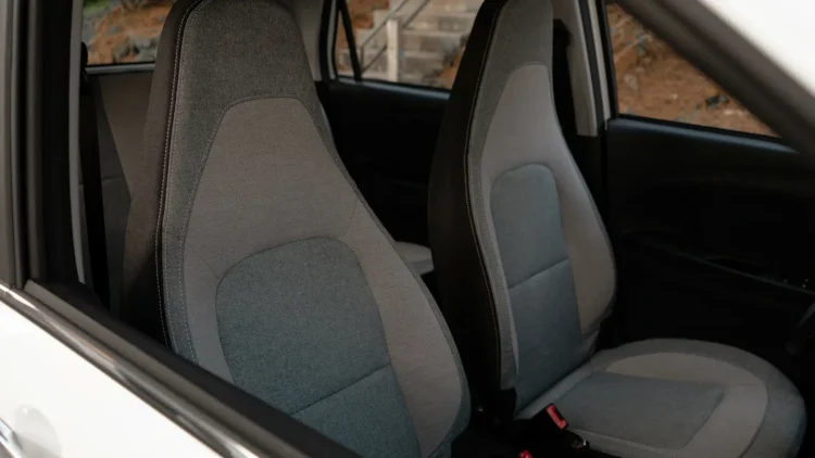 Gray two-tone cloth front bucket seats inside a Wink Mark3 electric microcar, viewed through the open passenger door.